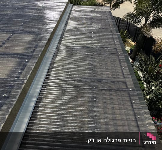 גג מתכת עם נוף של עצים ובניינים ברקע
